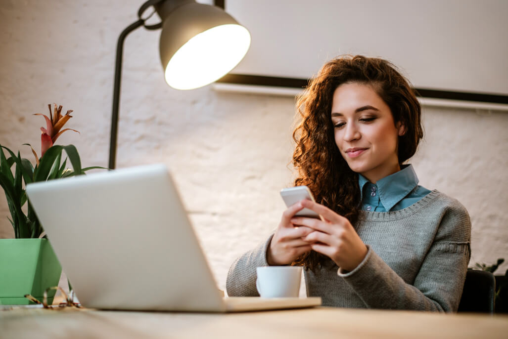 Imagebild Person aus der Generation Z am Schreibtisch mit Handy und Laptop