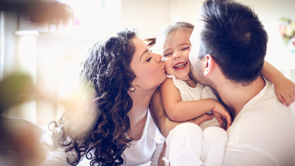 Imagebild: Mutter und Vater geben ihrem kleinen Kind einen Kuss auf die Wangen